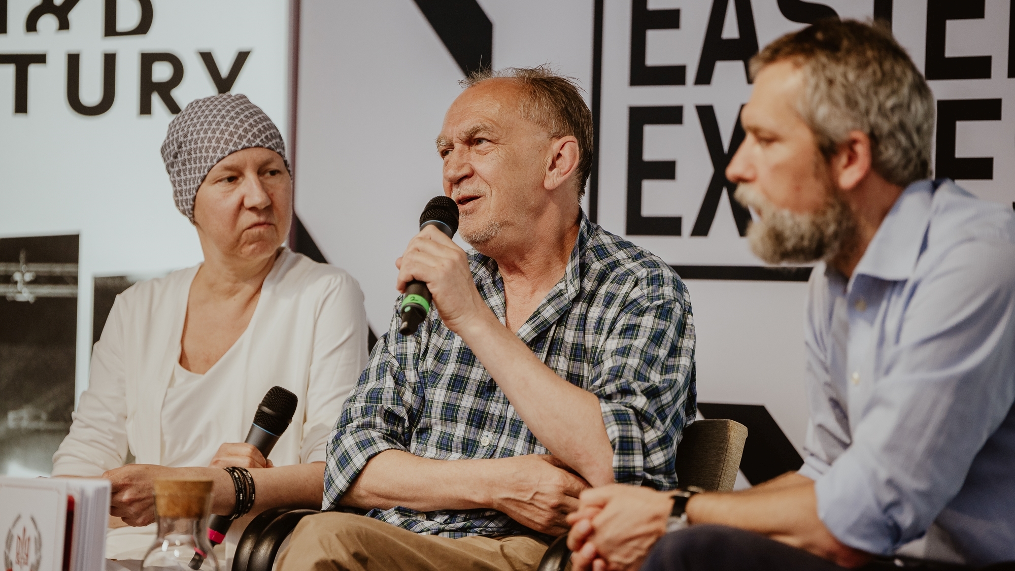 Dwaj mężczyźni i kobieta prowadzą debatę.